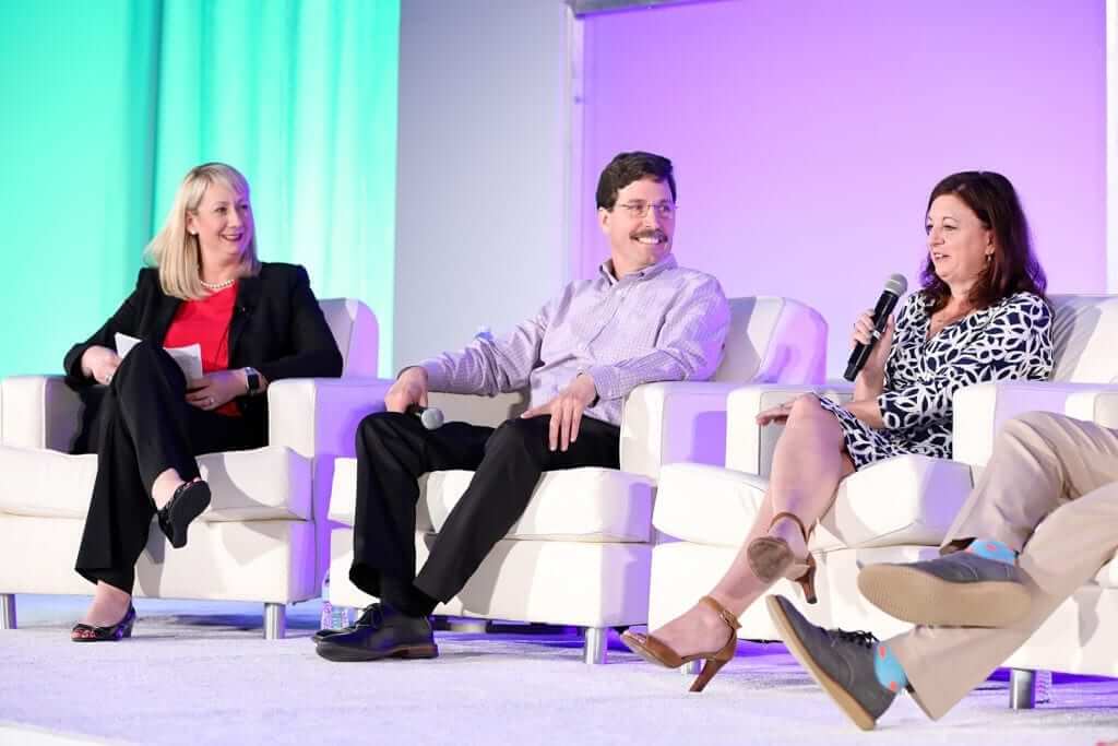 People on stage speaking to a crowd of business people