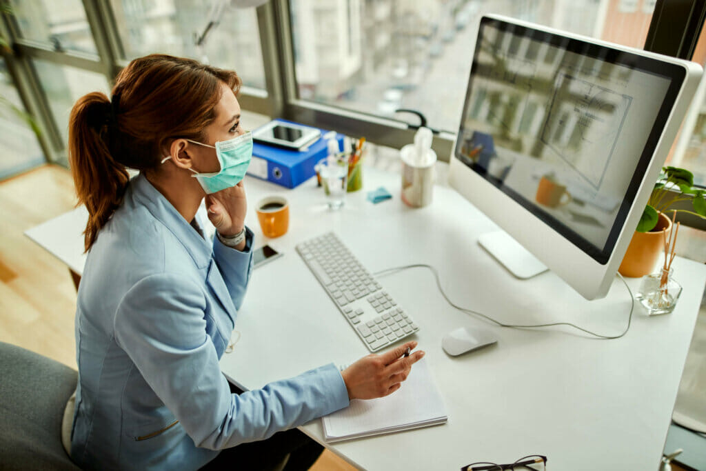 How COVID-19 has Changed HR: Female working on computer with mask