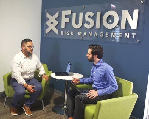 2 men sitting in front of large Fusion logo