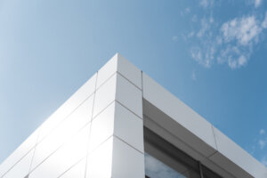 Building with white aluminum facade and aluminum panels against blue sky